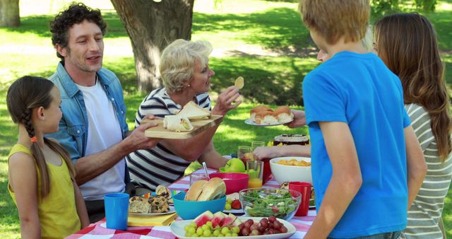 Family Enjoys Outdoor Picnic with Food and Laughter in Park - Download Free Stock Images Pikwizard.com