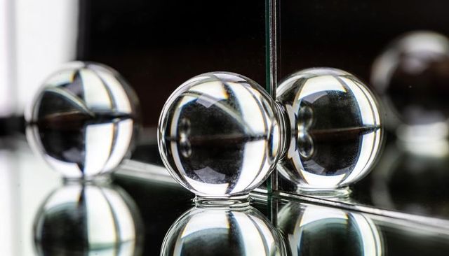Crystal sphere resting at mirror seam reflecting light and creating symmetrical refraction