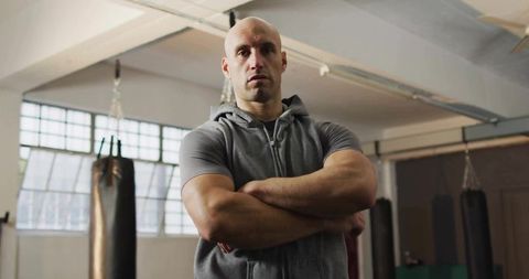 Strong athlete in boxing gym with arms crossed looking determined