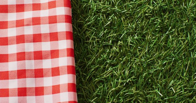 Image of gingham tablecloth with copy space on grass. Picnic day, leisure time, alfresco eating and lifestyle concept.
