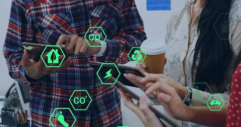 Coworkers collaborating with smartphones and tablets showing green sustainability icons