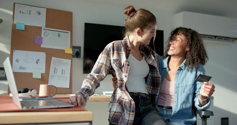 Diverse Women Collaborating and Sharing Credit Cards in Office