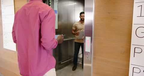Businessman waiting by elevator holding tablet