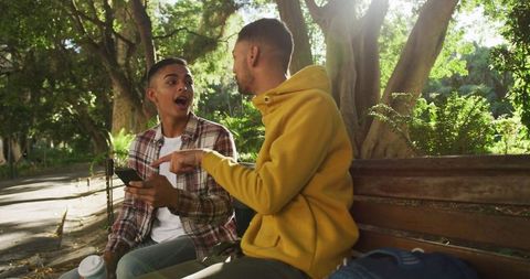 Friends Laughing and Using Smartphone in Sunny Park
