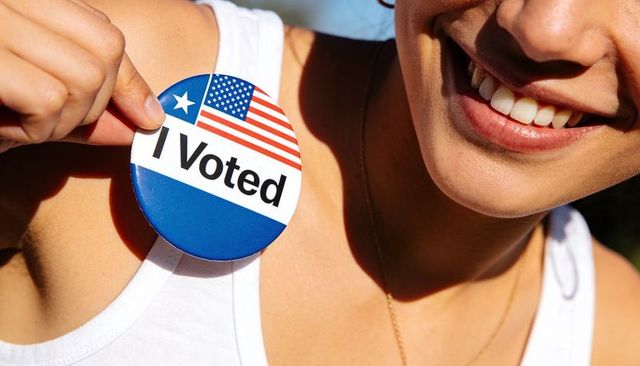 Smiling voter displaying i voted button on chest in sunlit portrait celebrating civic participation