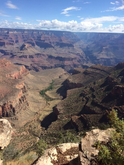 Grand Canyon landscape with cloudy sky showcasing monumental rocky cliffs and arid wilderness. Ideal for depicting the grandeur of nature, travel destinations, tourism ads, adventure holidays, and geographic educational materials.