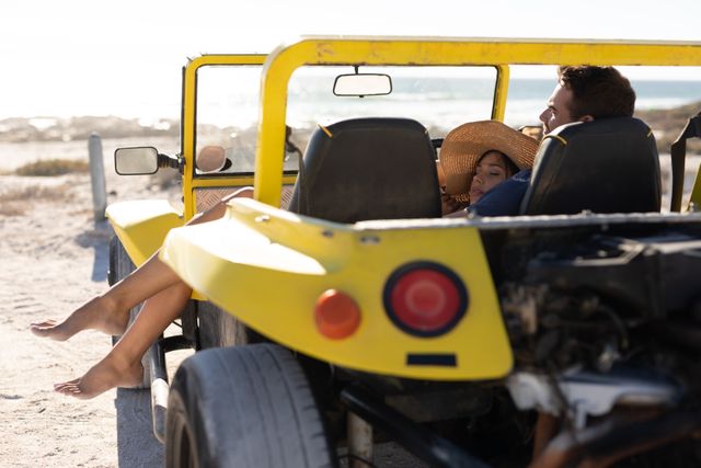 Couple enjoying a sunny day at the beach while relaxing in a yellow beach buggy. Ideal for use in travel blogs, vacation advertisements, romantic getaway promotions, and lifestyle magazines.