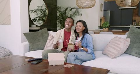 Young African American Couple Enjoying Drinks and Takeout at Home