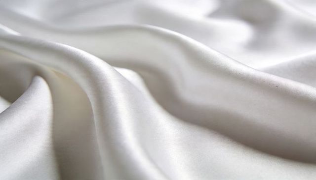White satin fabric draping in soft waves with smooth sheen and closeup texture