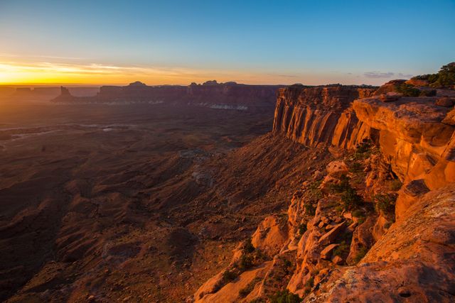 Sunrise casting a golden glow over Grand Canyon rock formations and vast desert. Ideal for travel and adventure marketing, nature documentaries, scenic calendars, and inspirational backgrounds.