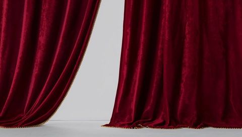 Hanging burgundy velvet curtains pooling on pale gray floor with gold bead trim