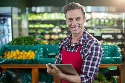 Grocery store employee using tablet in produce section