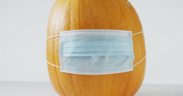 Pumpkin in Halloween decoration with a blue surgical mask. Ideal for promoting health and safety during Halloween festivities, addressing pandemic themes, and creating humorous or seasonal content for social media, blogs, or newsletters.