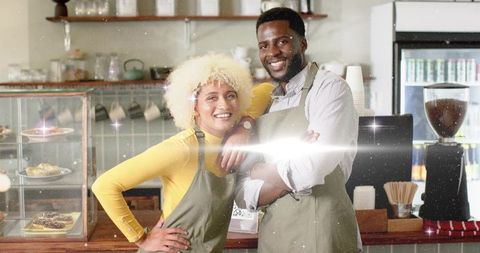 Baristas smiling in cozy coffee shop setting with baked goods display