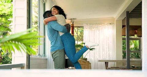 Happy couple embracing in sunlit room with cozy decor