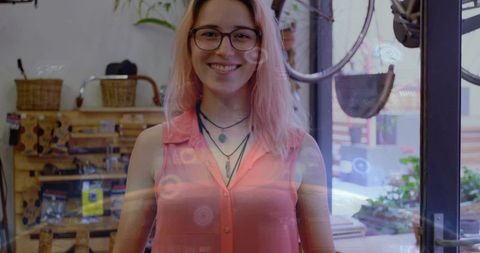 Smiling woman wearing coral blouse and glasses posing in boutique with reflections