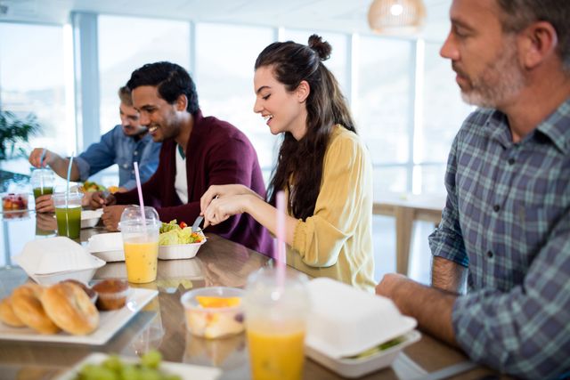 Creative business team enjoying a meal together in an office setting. Ideal for illustrating concepts of teamwork, office culture, and employee engagement. Perfect for use in corporate websites, HR materials, and articles about workplace dynamics.