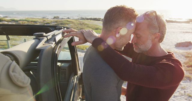 Happy caucasian gay male couple standing by car embracing on sunny day at the beach. summer road trip and holiday in nature.