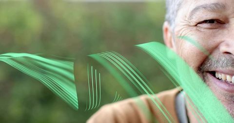 Smiling mature man showing half face with teal digital overlays in outdoor greenery