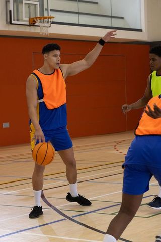 Male basketball players practicing team strategy on indoor court