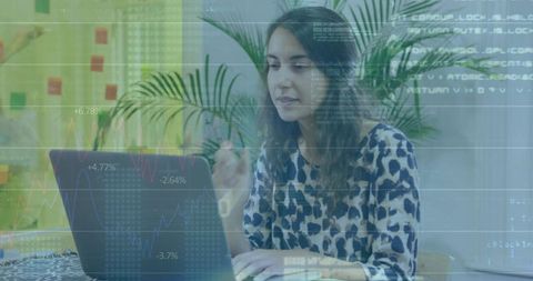 Young woman working on laptop with financial charts overlay in bright coworking workspace