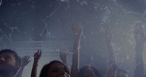 Concert crowd raising hands under bright stage lights and haze, neon nightlife energy