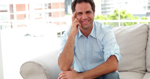 Cheerful man sitting on sofa in modern living room - Download Free Stock Images Pikwizard.com