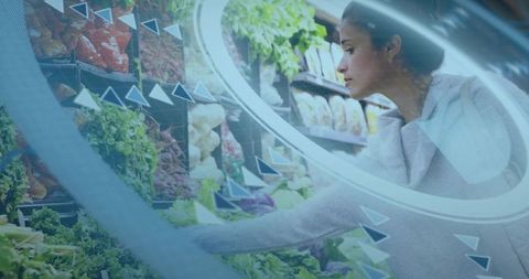 Young woman selecting fresh lettuce with futuristic data overlay in supermarket aisle