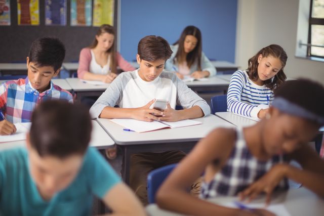 Student using mobile phone in classroom at school