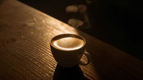 Steaming espresso cup on rustic wood table glowing in golden low light
