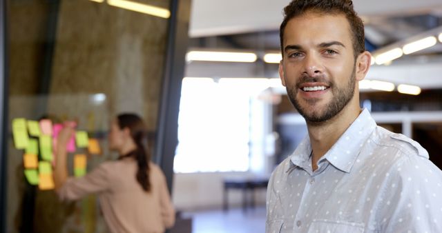 Young Professional Smiling in Office with Colleague Working - Download Free Stock Images Pikwizard.com