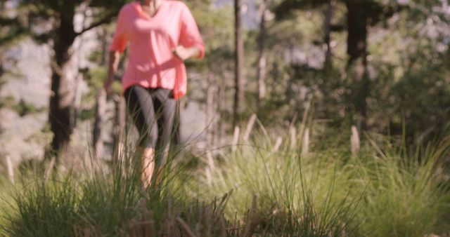 Woman jogging through forest on a sunny day