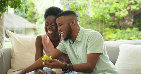 Joyful Couple Sharing Dessert on Comfortable Sofa Outdoors