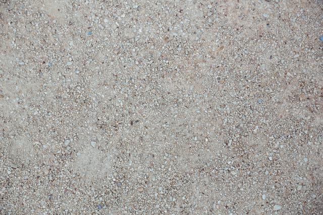 This image shows a rough cement floor surface with a gritty texture. It is ideal for use in construction and building-related projects, as a background for industrial themes, or for design purposes where a solid, foundational texture is needed.