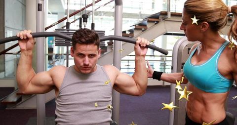 Male Athlete Performing Lat Pulldown While Female Trainer Coaching in Modern Gym