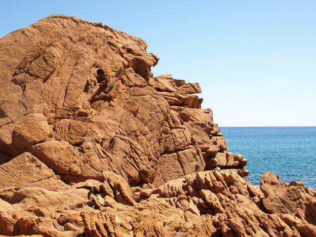Rugged cliff overlooking a blue ocean under a clear sky, perfect for travel brochures, nature blogs, adventure magazines, and posters showcasing natural beauty and outdoor activities. Ideal for promoting serene coastal destinations and geological features.
