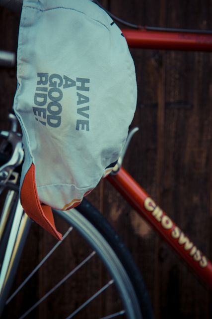 Cap hanging on handlebar of vintage Crosswise bicycle with message 'Have a Good Ride'. Ideal for promotions on cycling, sportswear, motivational content, outdoor adventures.