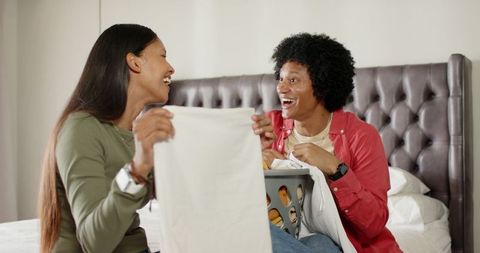 Diverse Couple Folding Laundry Together in Cozy Bedroom