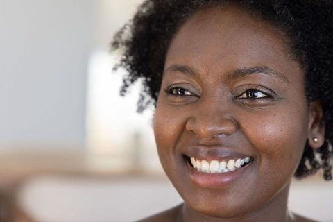 Confident african american woman smiling closeup headshot in cozy living room warm light