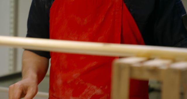 Craftsperson wearing red apron working with wooden dowel - Download Free Stock Images Pikwizard.com