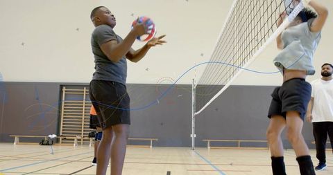 Preparing pass and jumping to block at net during indoor volleyball team practice