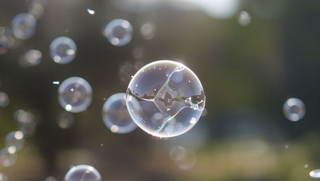 Iridescent soap bubble floating in sunlit park with bokeh reflections and smaller orbs