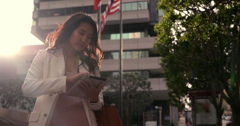 Asian Businesswoman Checking Tablet in Urban Environment