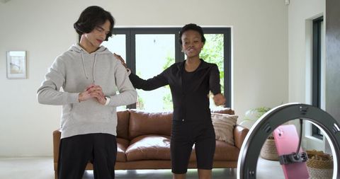 Friends filming fitness and lifestyle vlog at home with ring light smartphone collaboration