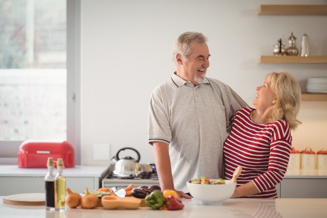 Smiling senior couple embracing each other in kitchen at home