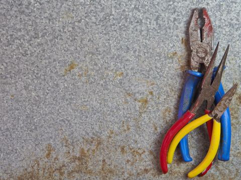 Set of old rusty pliers on worn metal background