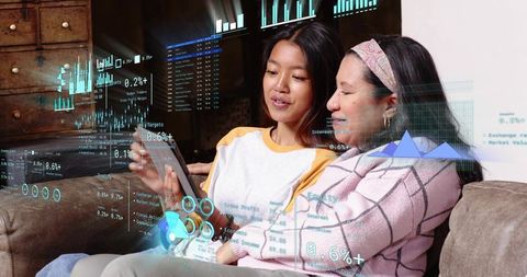 Mother and daughter exploring augmented reality finance charts on tablet in cozy living room