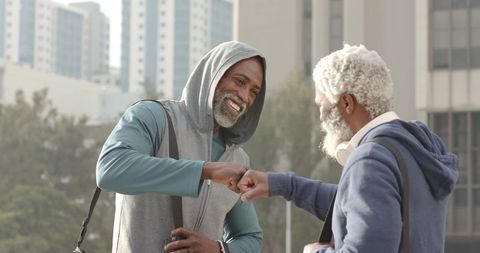 African American Senior Friends Fist Bumping and Smiling in Urban Athleisure