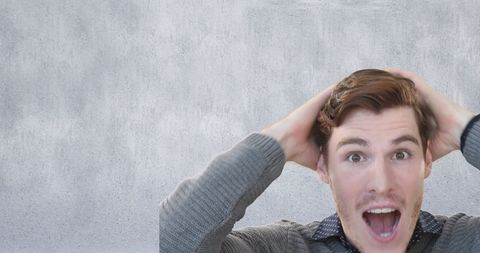 Surprised Young Man with Hands Over Head Looking Amazed