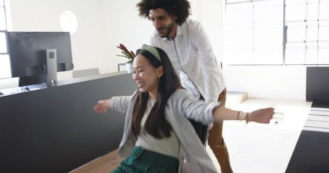 Business Colleagues Having Fun in Office with Rolling Chair